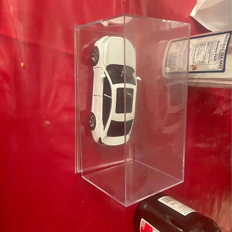 Diecast car model in clear display box, white with black detailing, front view.