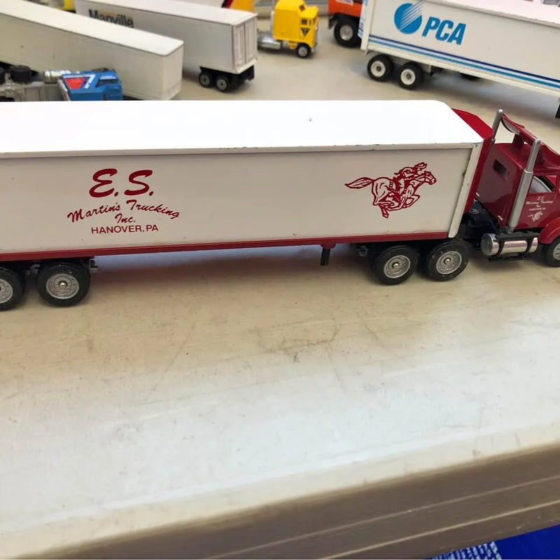Vintage diecast tractor trailer with red-and-white side panel and lettering, visible wheels