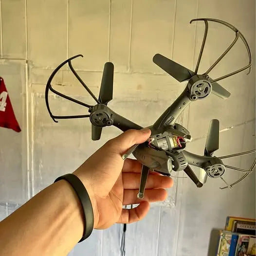 Grey quadcopter drone in hand, four propellers and front camera module
