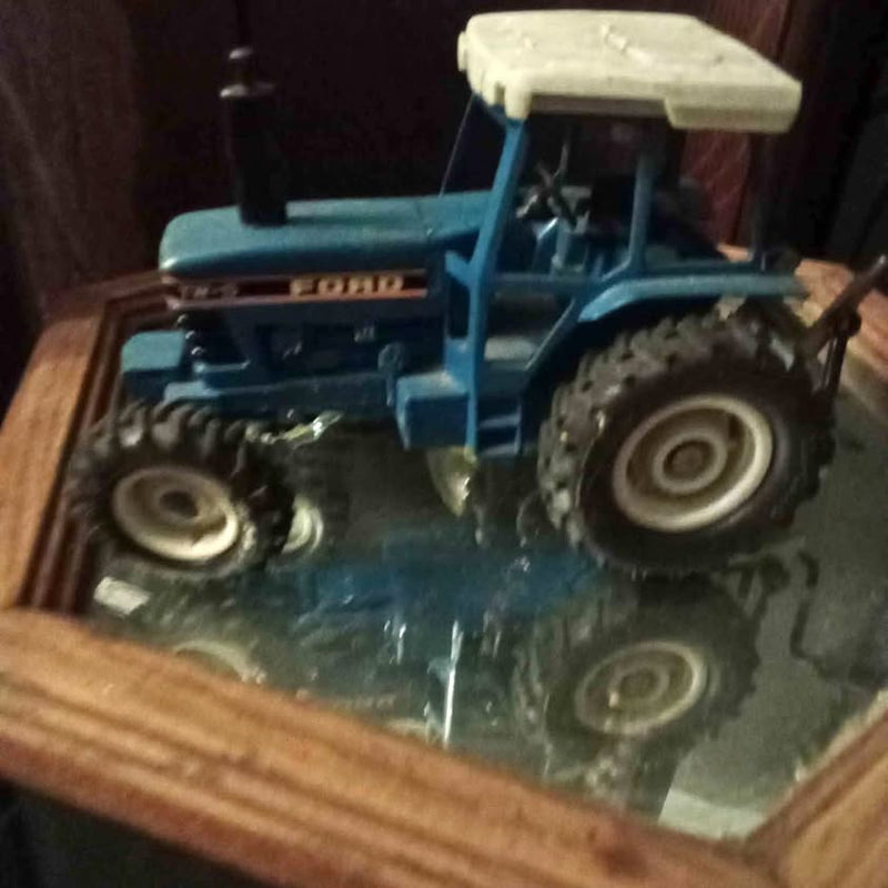 Blue diecast tractor with enclosed cab, front grille, and large tires