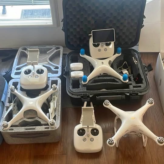 DJI Phantom drones, white quadcopters with remote controllers and hard cases