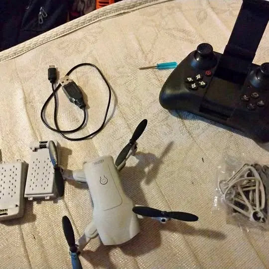 White quadcopter drone with black controller, cables, and charging accessories