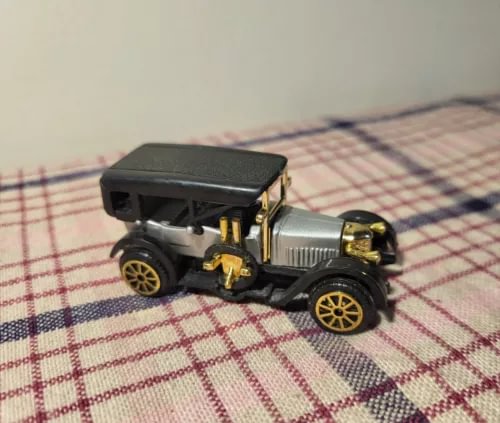 Diecast classic car model with black body and gold trim, open cabin, detailed wheels