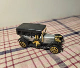 Diecast classic car model with black body and gold trim, open cabin, detailed wheels