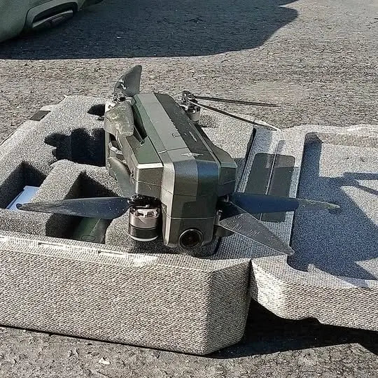 Camera drone with folded rotors resting in a gray foam carrying case
