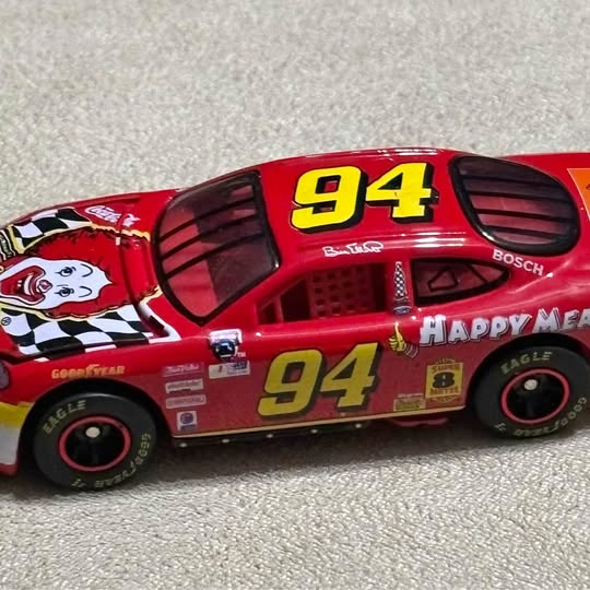 Red diecast race car with yellow number 94 decals and black wheels