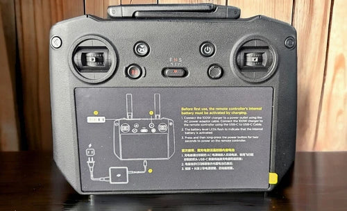 Gray DJI remote controller back with ports, switches, and battery compartment label