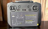 Gray DJI remote controller back with ports, switches, and battery compartment label