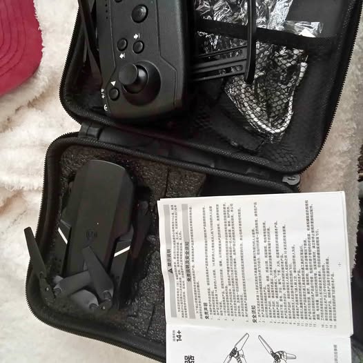 Black foldable drone in hard-shell carrying case with instruction manual