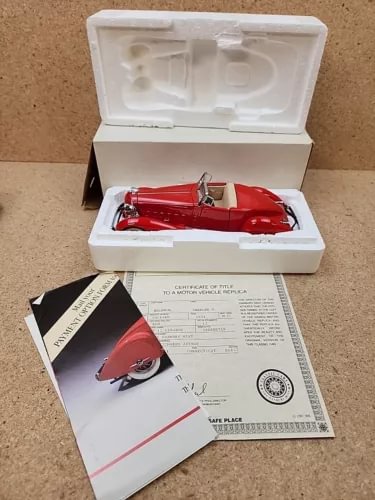 Danbury Mint red diecast car in open white display box with paperwork and certificate