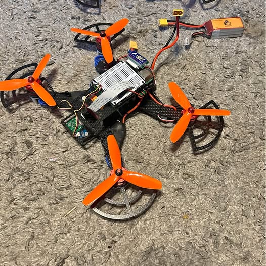 Orange four-propeller quadcopter drone with visible circuit board components