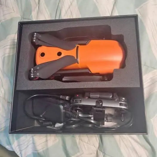 Orange drone inside a box with folded prop arms and gray controller