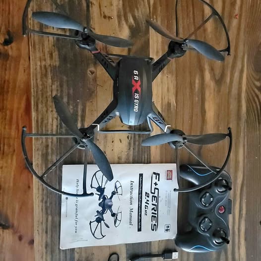 Black quadcopter drone with four propellers, remote controller and packaging