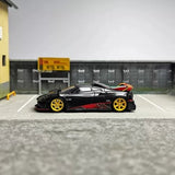 Black diecast model car with red accents and yellow wheels, side view