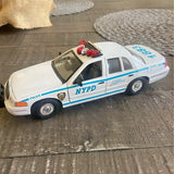 White NYPD diecast police car with blue stripe and red rooftop lights