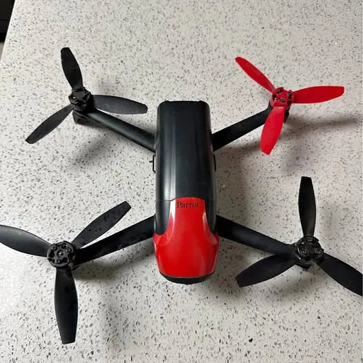 Quadcopter drone with four propellers, red and black body.