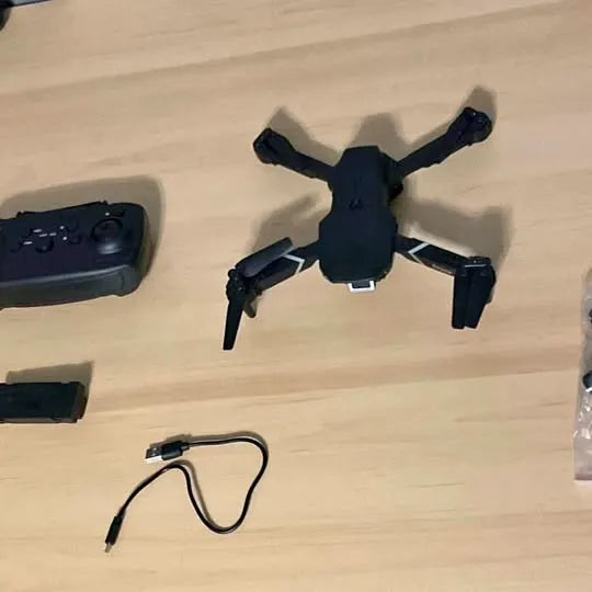 Black quadcopter drone with four propeller arms and attached body on tabletop