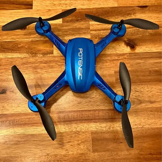 Blue quadcopter drone with four propellers and front camera housing