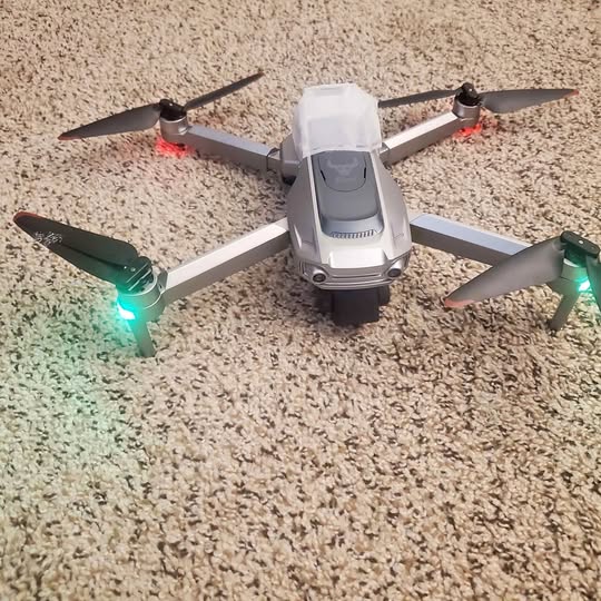 White and gray quadcopter drone with four propellers and LED lights