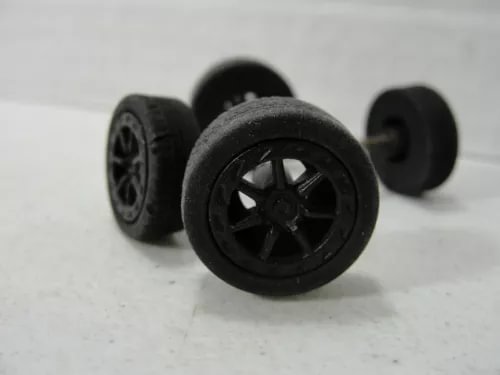 Black diecast wheel set with multi-spoke rims and rubber tires, close-up view
