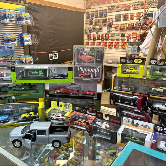 Diecast car lot with assorted model cars in clear display cases, including trucks