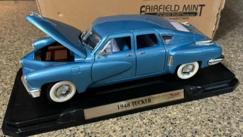 Blue 1948 Tucker Torpedo diecast model car on display base, hood open