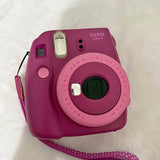 Purple Instax mini 9 instant camera with lens, flash window, and wrist strap