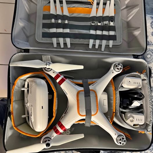 White quadcopter drone with four propellers, partially in carrying case