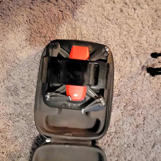 Compact black drone with orange components in an open hard case