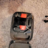Compact black drone with orange components in an open hard case