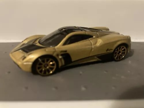 Gold 1:64 diecast sports car model with black wheels, side view