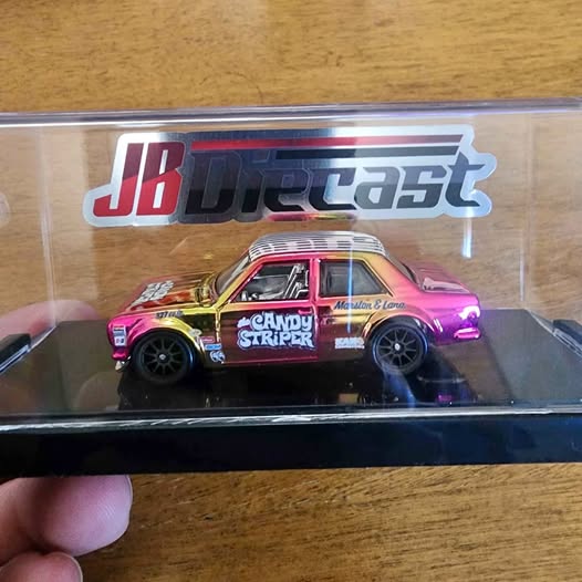 Diecast model race car in clear box, black with pink hood and side decals