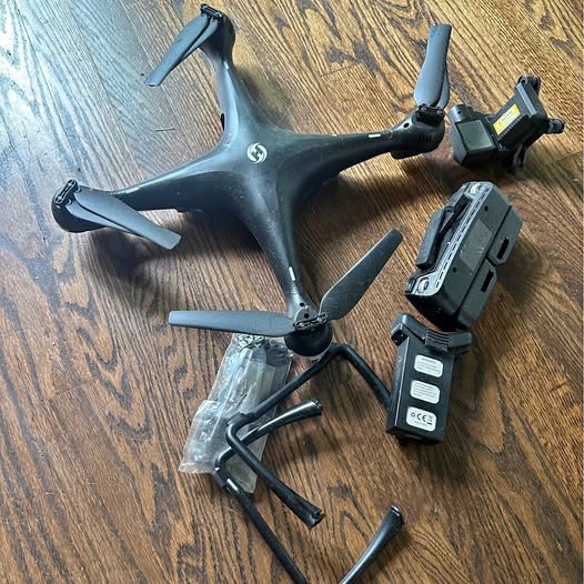 Gray quadcopter drone with propellers, remote controller, and battery pack