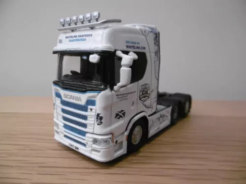 White diecast Scania tractor truck with blue stripe, cab detail, front three-quarter view