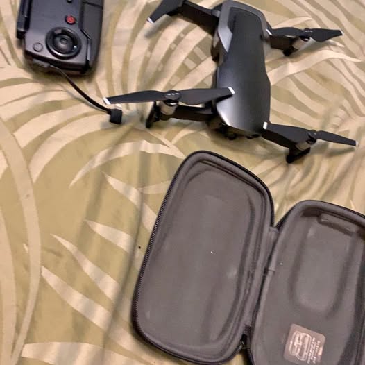 Folded quadcopter drone with propellers and dark gray hard carry case with zipper