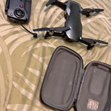 Folded quadcopter drone with propellers and dark gray hard carry case with zipper