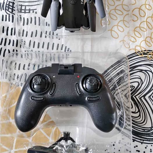 Black RC transmitter remote with two joysticks and control buttons in plastic packaging