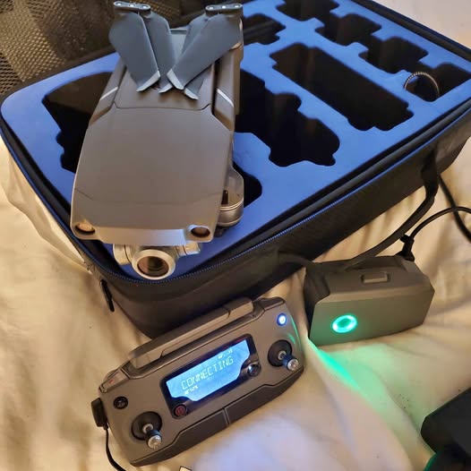 Gray quadcopter drone with propellers and lit controller screen in a case