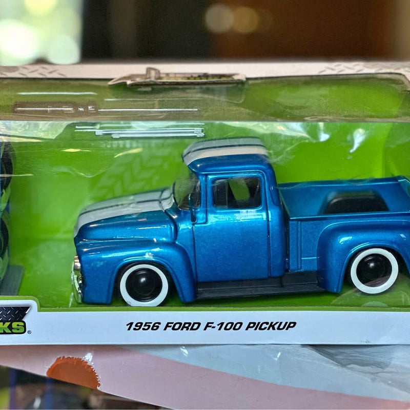 Blue diecast Ford F-100 pickup truck model with open bed, on retail box