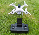 White RC quadcopter drone with camera and black remote controller on grass