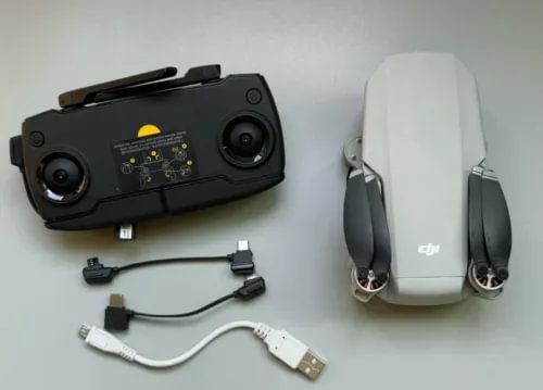 Black DJI Mini RC controller with attached cables and white drone body