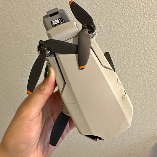 DJI Mini 2 drone with propellers, off-white body and orange accents
