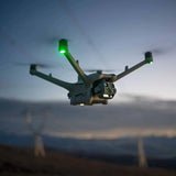 Enterprise quadcopter drone with four arms and green navigation lights in flight