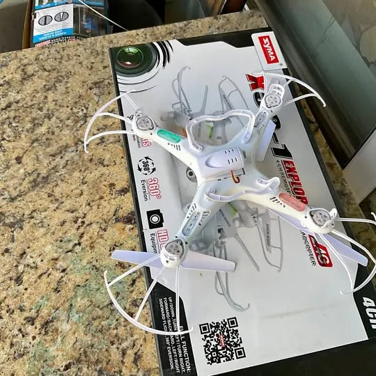 White quadcopter drone with camera, four propellers and landing gear