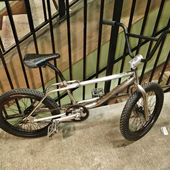 Silver mountain bike with black tires, front suspension fork and flat handlebar