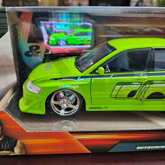 Green 1:24 diecast sports car model in clear display box, front-left view