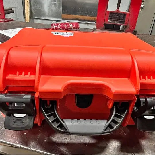 Orange protective drone case with molded handle, vents, and black cable connectors