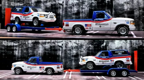 White and blue diecast toy pickup trucks with red trailer hitch and tow dolly