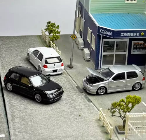 Three 1:64 scale diecast VW-style hatchback toy cars: black, silver, and white.