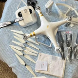 White quadcopter drone with five gold-striped propellers and remote control kit